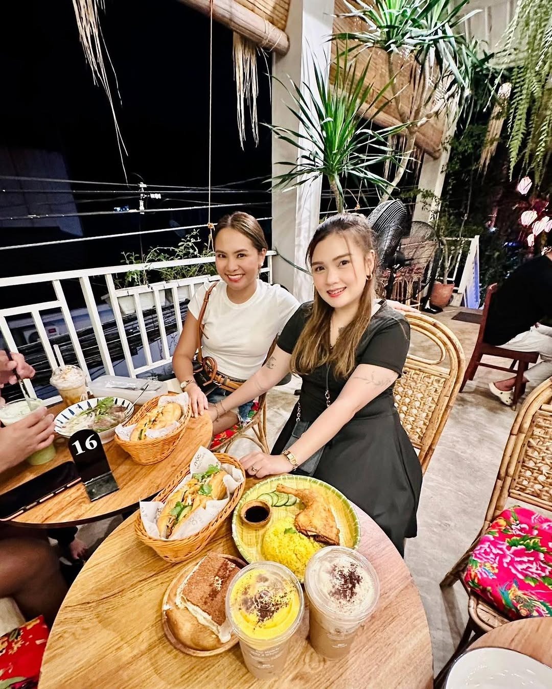 Two women at table with food and drinks at MỘC Cafe